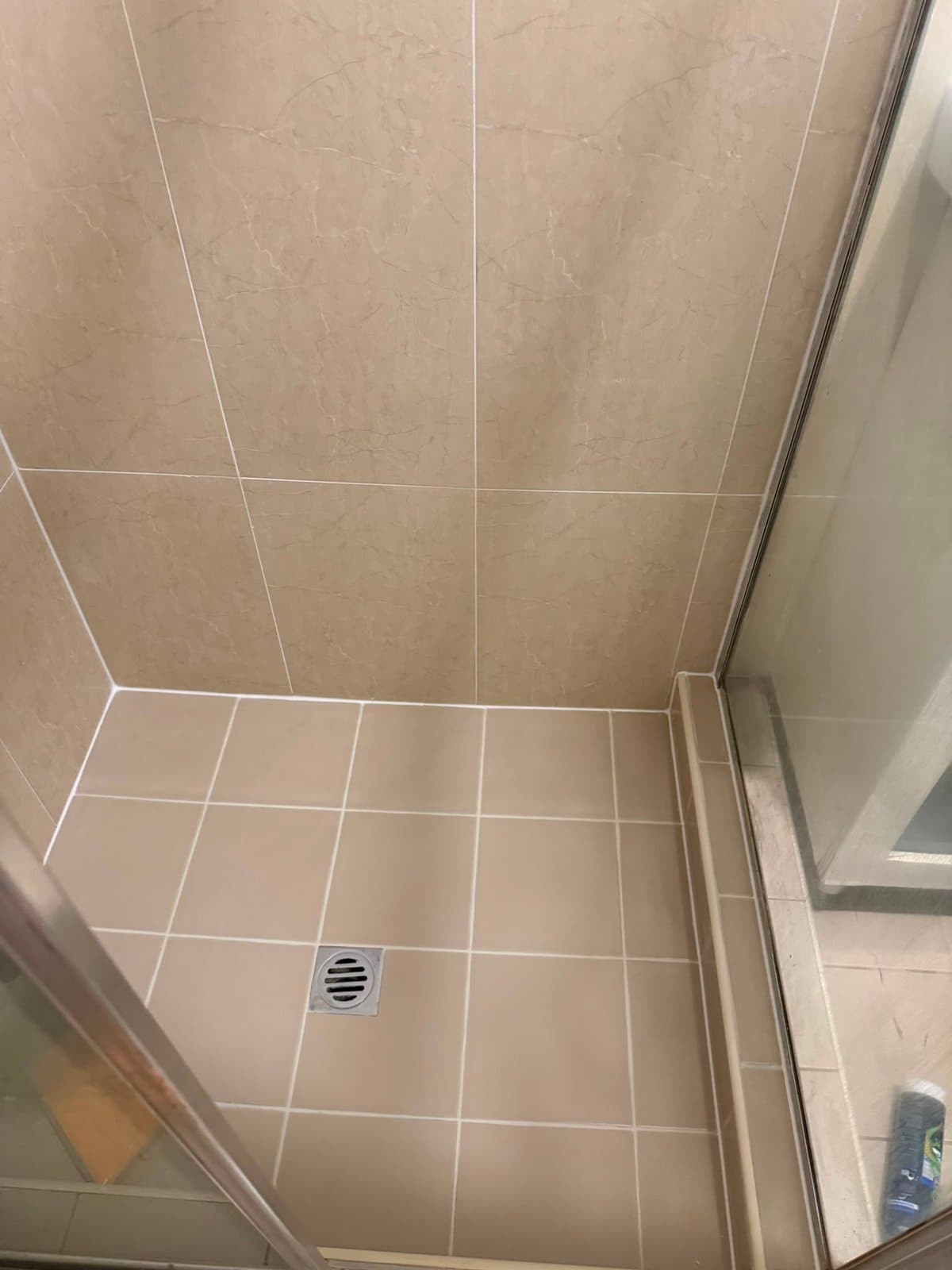 The same shower with clean walls and fresh white grout across the floor