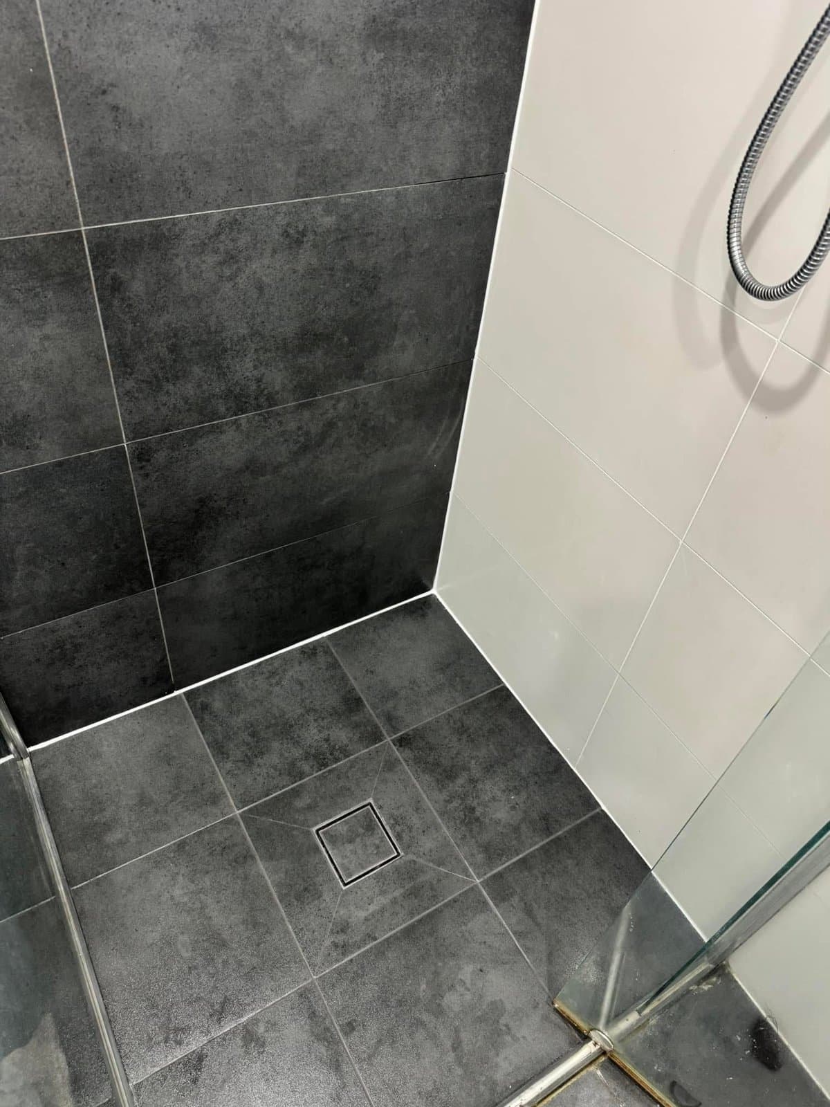 The same shower cleaned back, with the grout lines and floor restored