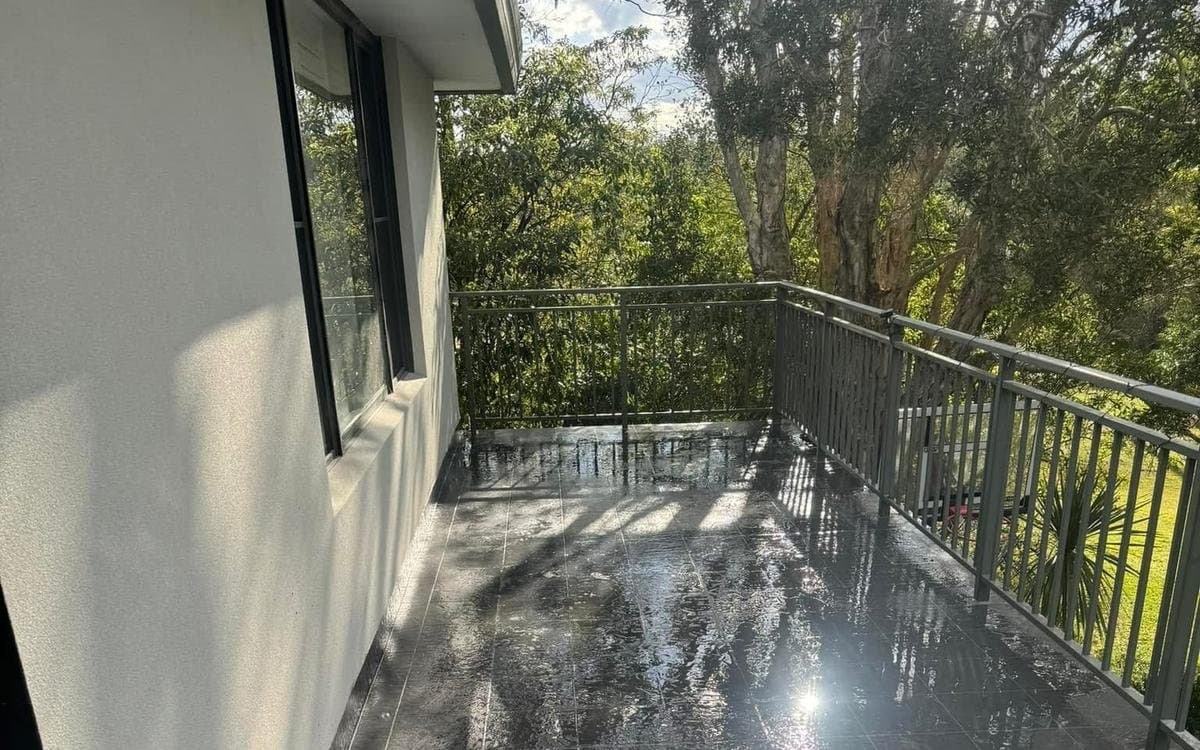 A tiled Sydney balcony with a glass and steel balustrade after waterproofing
